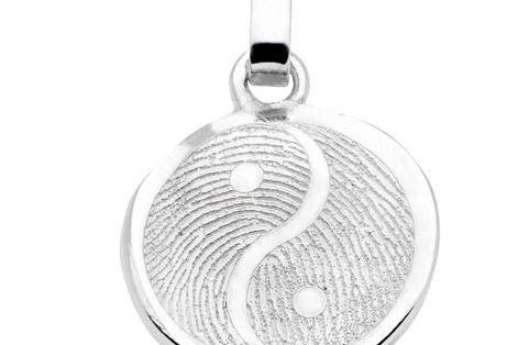 Fingerabdruck auf einem runden silbernen Anhänger im ying und yang Stil